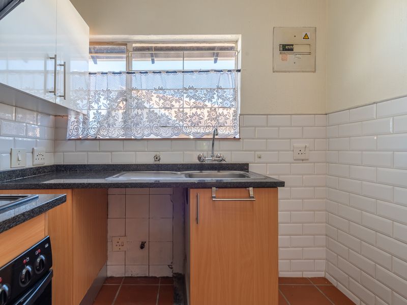 A functional kitchen featuring subway tile backsplash, granite countertops, a double basin sink, and a built-in oven, with some cabinetry maintenance required.