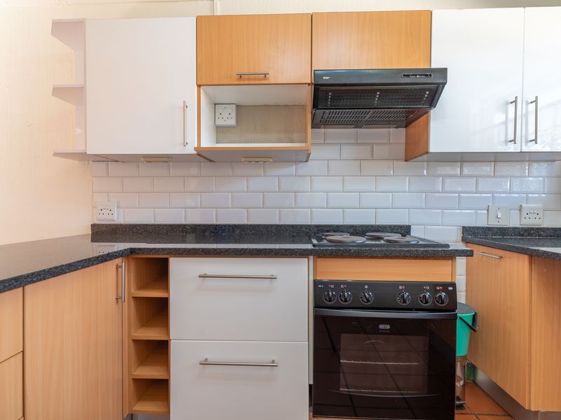 A functional kitchen featuring two-tone cabinetry, granite countertops, subway tile backsplash, and a built-in electric oven with extractor fan.