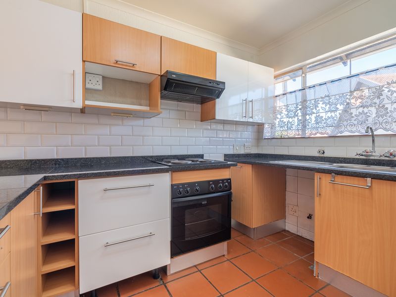 Functional kitchen featuring two-tone cabinetry, subway tile backsplash, built-in oven with hob, and tiled flooring with a window overlooking the exterior.