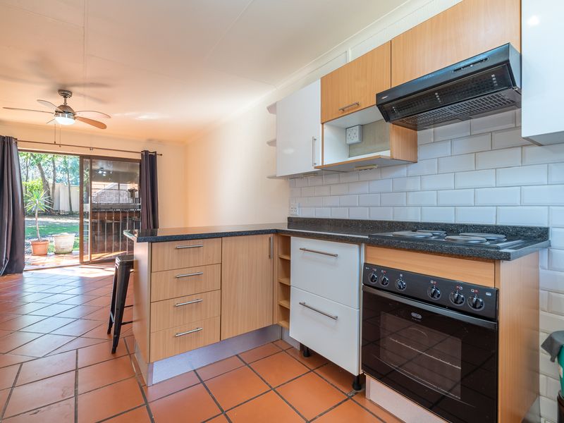 Open-plan kitchen featuring wood-finish cabinetry, granite countertops, and a subway tile backsplash, flowing directly onto a patio area through sliding glass doors.