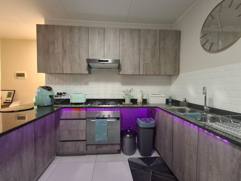A modern kitchen featuring wood-look cabinetry, granite countertops, a subway tile backsplash, and integrated stainless steel appliances.
