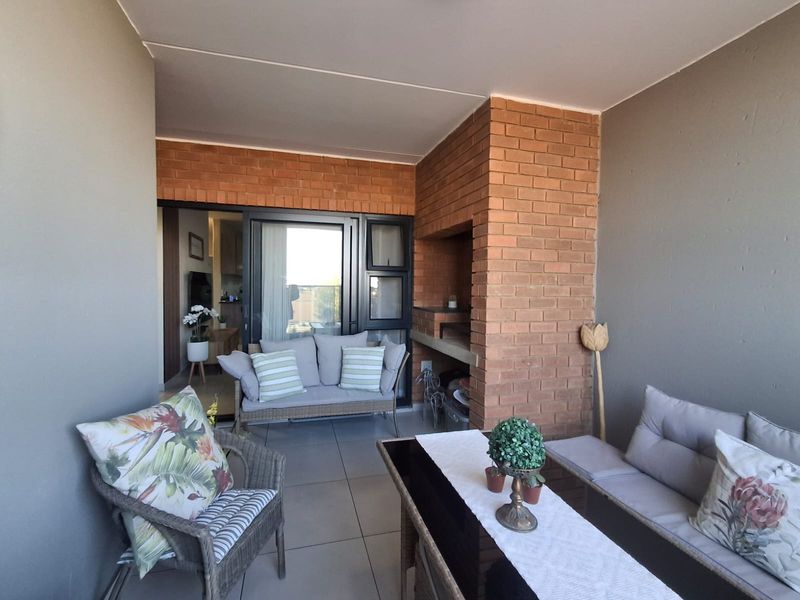 A covered balcony featuring a built-in brick braai, tiled flooring, and direct access to the interior living space through sliding glass doors.