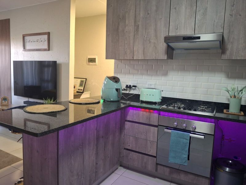 Modern open-plan kitchen featuring granite countertops, subway tile backsplash, built-in oven, gas hob, and stylish under-counter LED lighting.