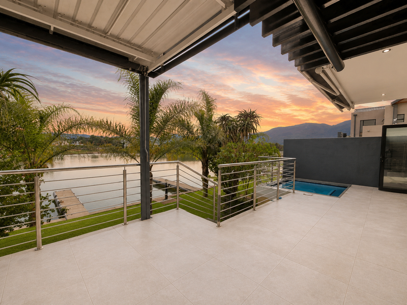 A modern covered patio featuring tiled flooring, stainless steel railings, and a private plunge pool overlooking the lake and mountain views.