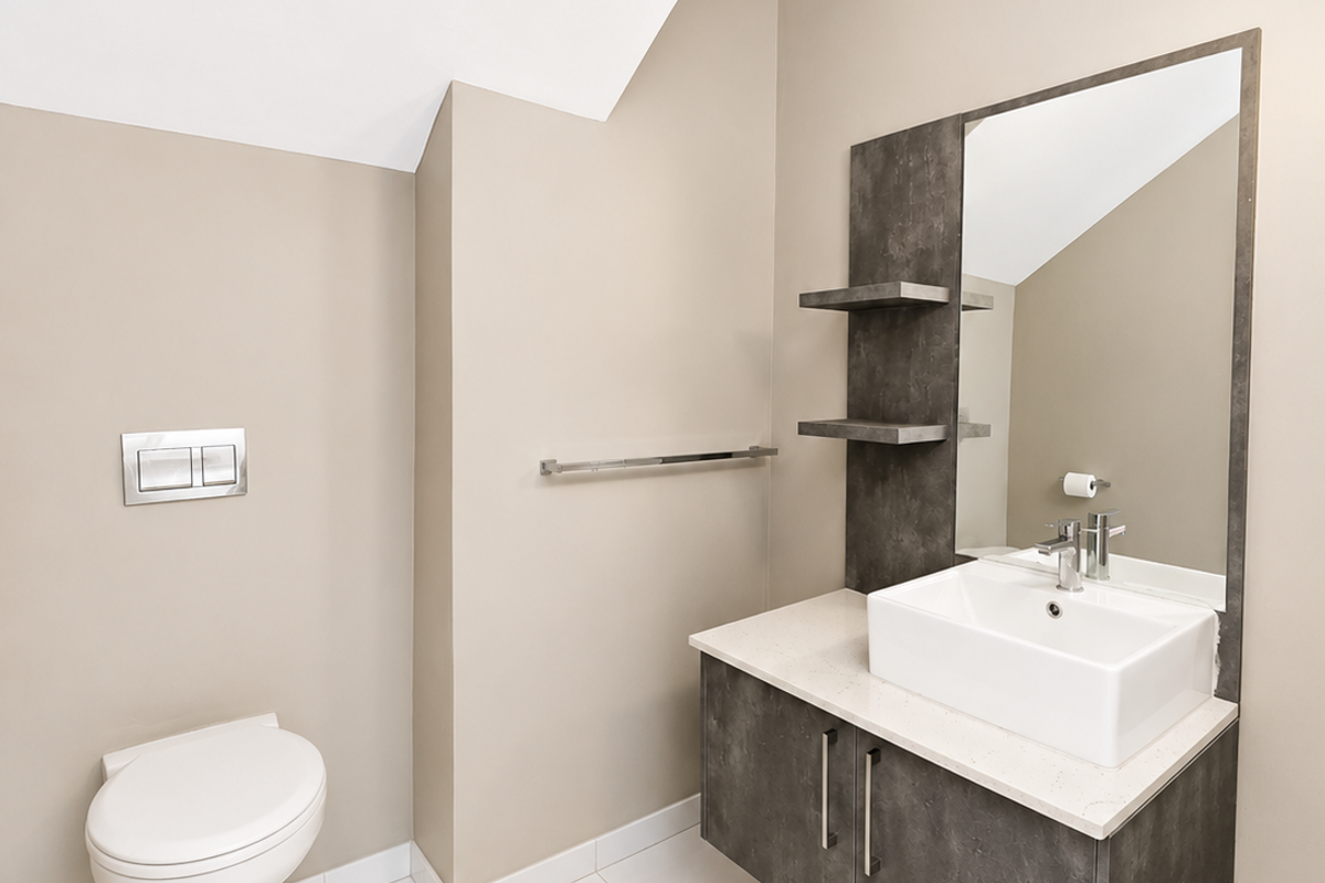 Modern bathroom featuring a wall-hung toilet with concealed cistern, floating vanity with countertop basin, and neutral tiled flooring.