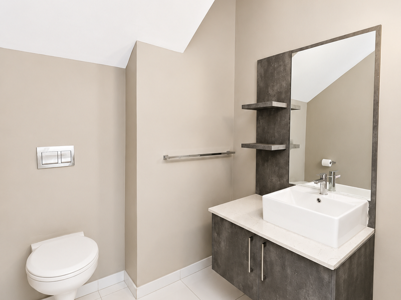 Modern bathroom featuring a wall-hung toilet with concealed cistern, floating vanity with countertop basin, and neutral tiled flooring.