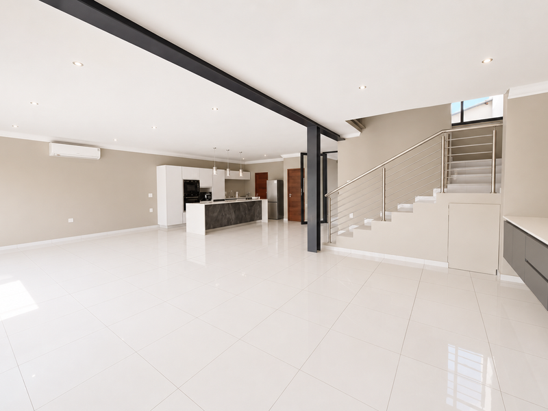 Spacious open-plan living area featuring a modern kitchen with island, sleek tiled flooring, and a contemporary staircase with stainless steel balustrades.