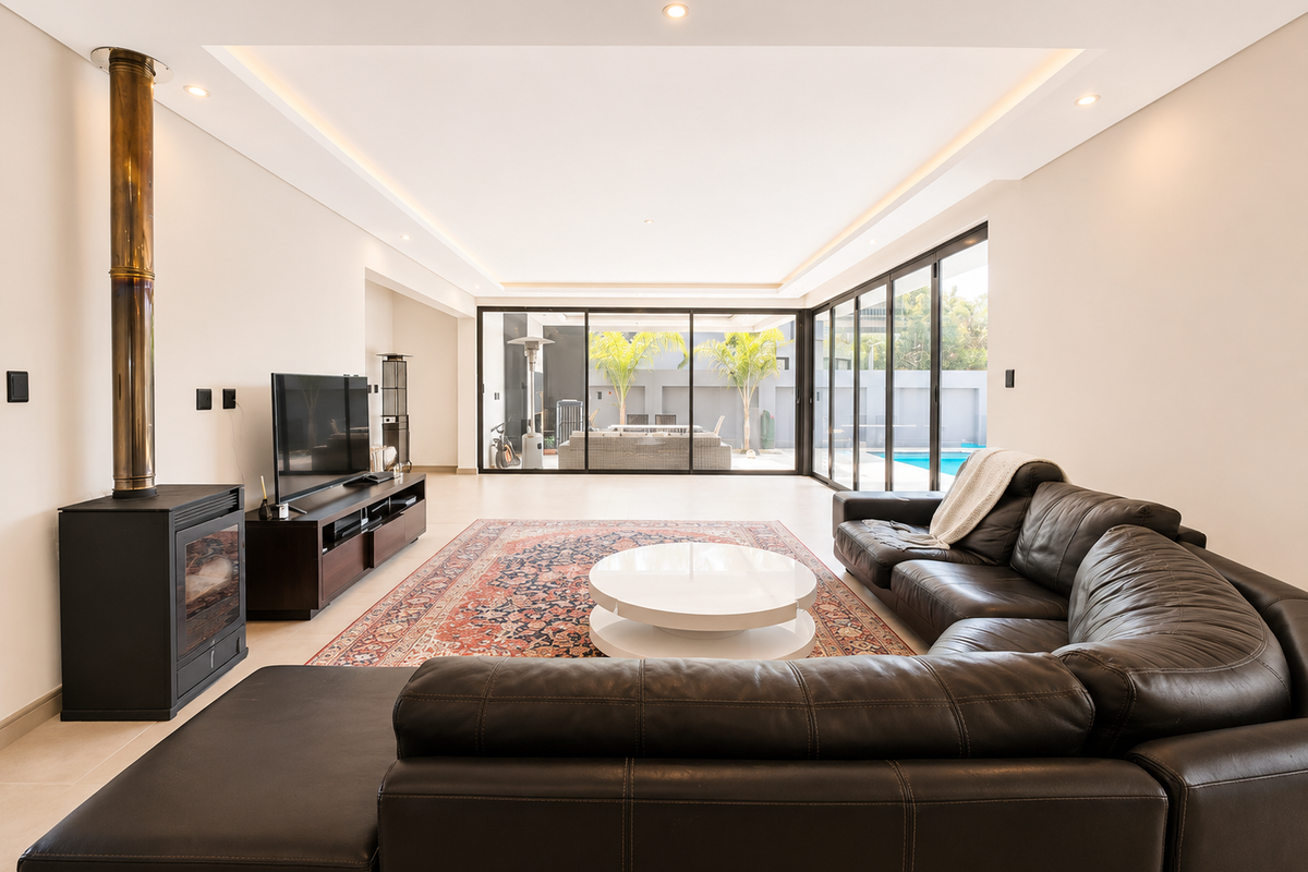 Spacious living room featuring a modern freestanding fireplace, recessed ceiling lighting, and large sliding glass doors opening to the outdoor pool area.