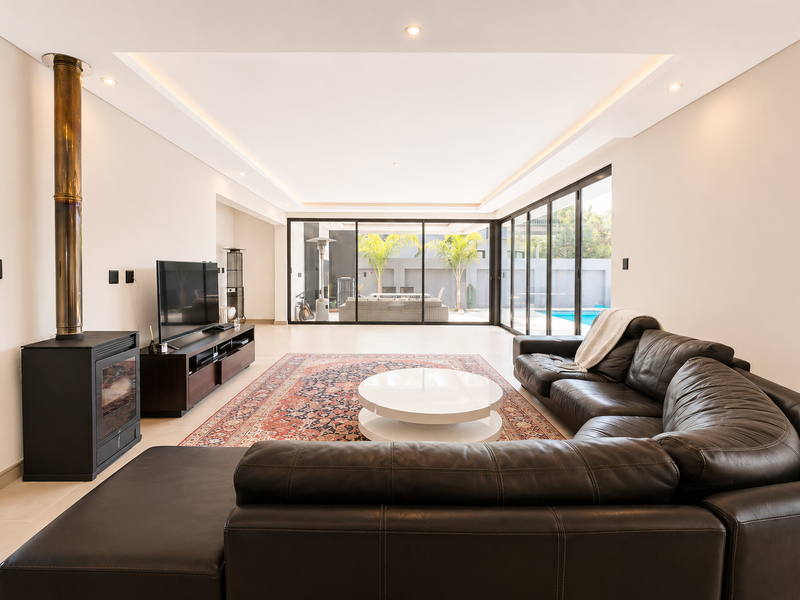 Spacious living room featuring a modern freestanding fireplace, recessed ceiling lighting, and large sliding glass doors opening to the outdoor pool area.
