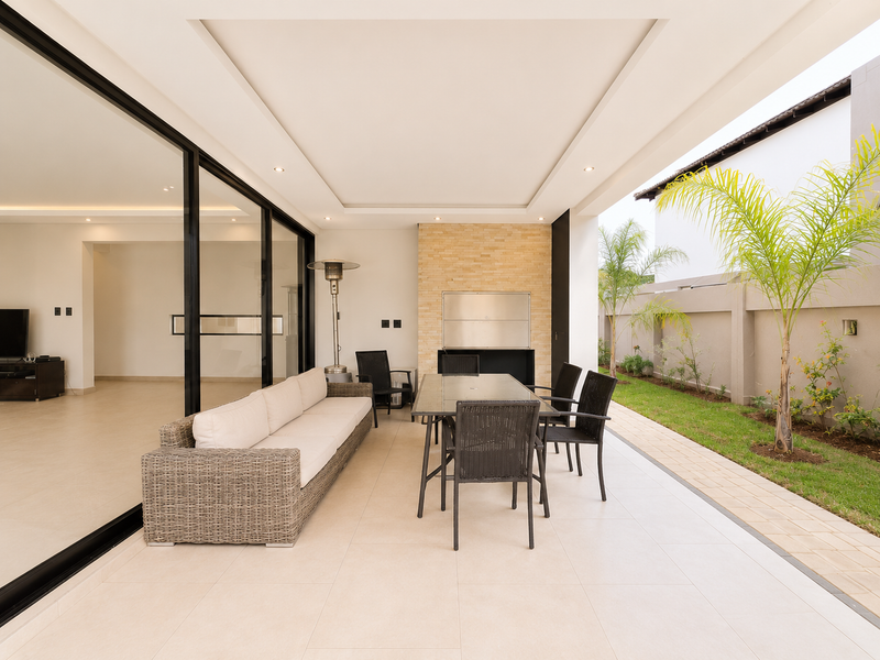 Spacious covered patio featuring a built-in braai, stone feature wall, and large sliding glass doors connecting to the interior living area.
