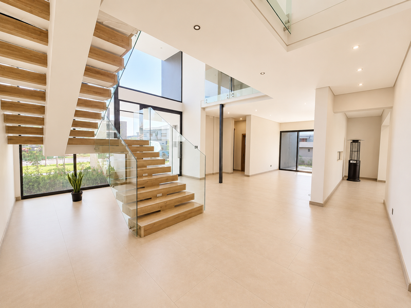 Spacious double-volume entrance hall featuring a modern floating timber staircase with glass balustrades and large windows providing abundant natural light.