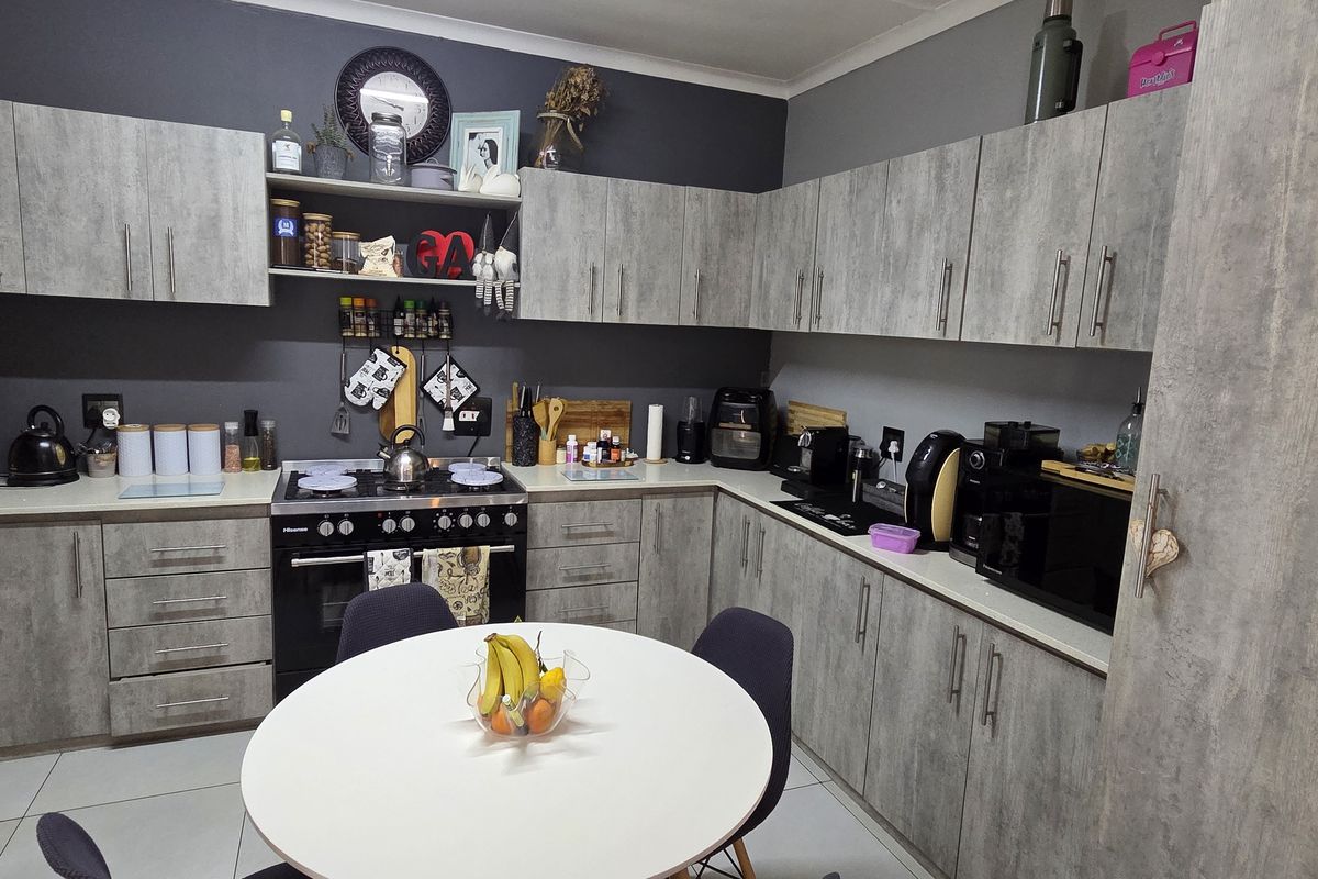 A functional kitchen featuring grey wood-look cabinetry, dark grey walls, tiled flooring, and a built-in gas stove with oven.