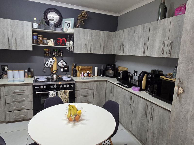 A functional kitchen featuring grey wood-look cabinetry, dark grey walls, tiled flooring, and a built-in gas stove with oven.