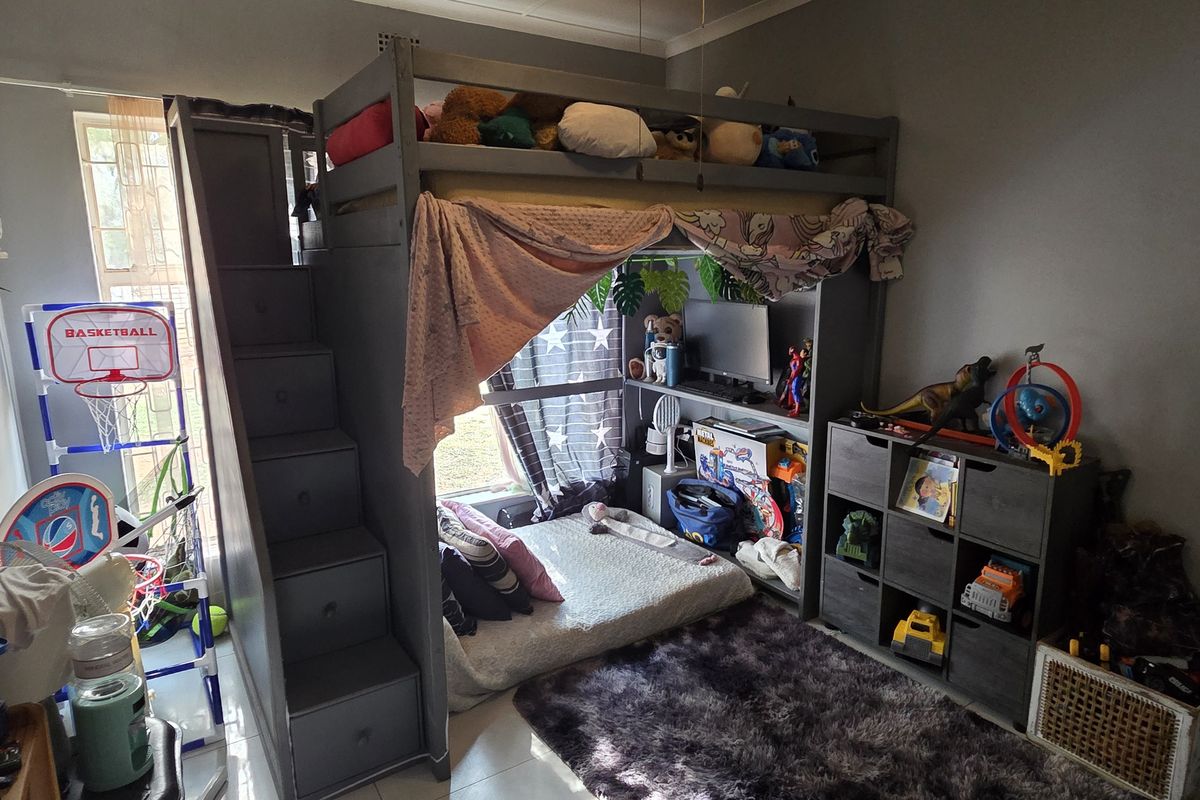 A bedroom featuring tiled flooring and a window, currently utilized as a child's room with built-in loft bed structure.