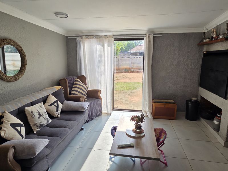 A living room featuring tiled flooring, a built-in fireplace, and a sliding glass door providing direct access to the rear garden.