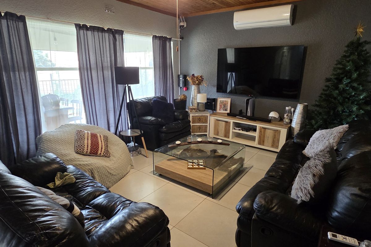 A comfortable living room featuring tiled flooring, a timber-paneled ceiling, and a wall-mounted split-system air conditioner.