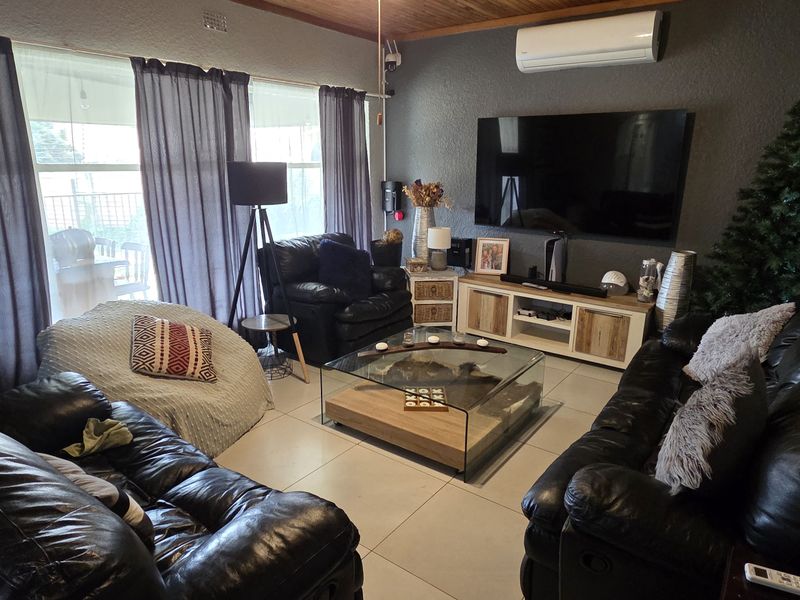 A comfortable living room featuring tiled flooring, a timber-paneled ceiling, and a wall-mounted split-system air conditioner.