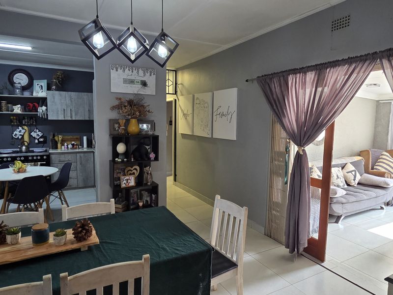 Open plan living and dining area featuring tiled floors, modern kitchen cabinetry, and direct access to an adjacent lounge space.