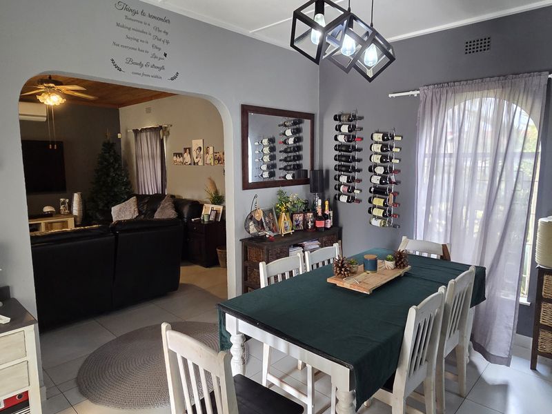 A dining room featuring tiled flooring, a decorative archway leading to the living area, and a wall-mounted wine rack.
