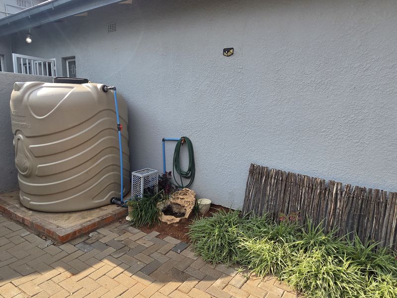 Rear courtyard area featuring a large water storage tank, gas geyser, and paved flooring, providing functional utility space for the property.