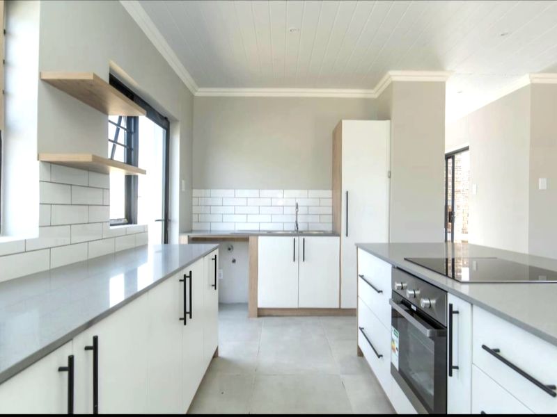 Modern kitchen featuring white shaker cabinetry, quartz countertops, subway tile backsplash, built-in oven, and a central island with an integrated cooktop.