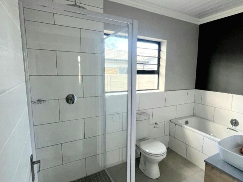 Modern bathroom featuring a glass-enclosed shower, built-in bathtub, vessel sink vanity, and contemporary subway tile finishes.