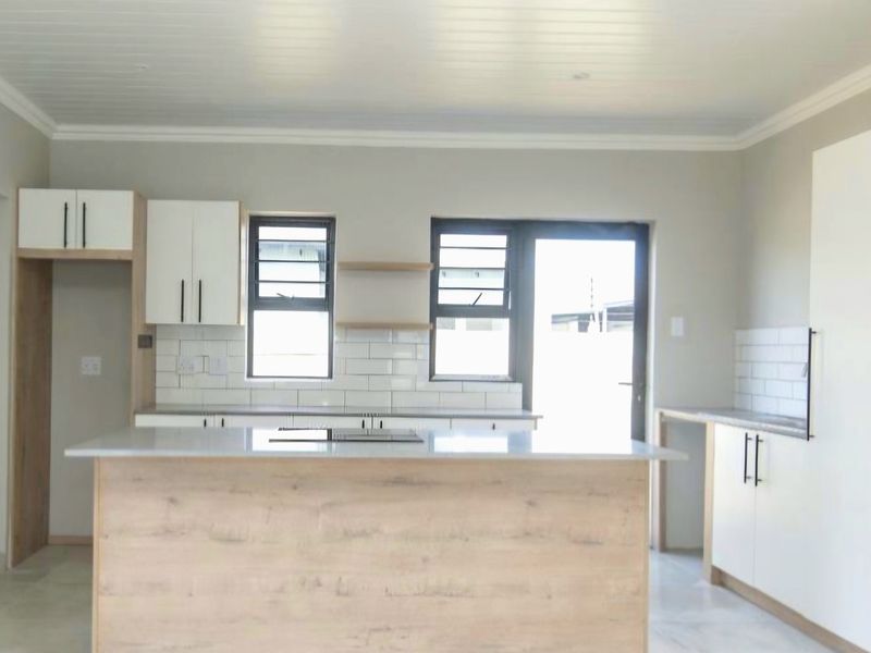 Modern kitchen featuring a central island, stone countertops, subway tile backsplash, and ample built-in cabinetry with a clean, contemporary finish.