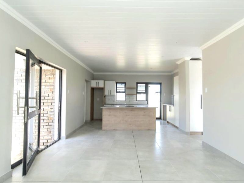 Spacious open-plan living and kitchen area featuring modern cabinetry, a central island, tiled flooring, and large sliding doors leading to the exterior.