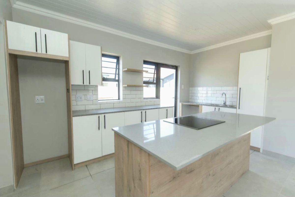 Modern, bright kitchen featuring a central island with a built-in hob, quartz countertops, white cabinetry, and a stylish subway tile backsplash.