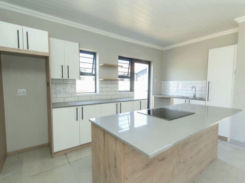 Modern, bright kitchen featuring a central island with a built-in hob, quartz countertops, white cabinetry, and a stylish subway tile backsplash.