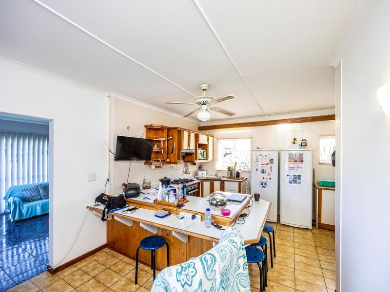 A functional kitchen featuring built-in wooden cabinetry, a tiled backsplash, a breakfast bar, and tiled flooring, offering potential for a modern update.