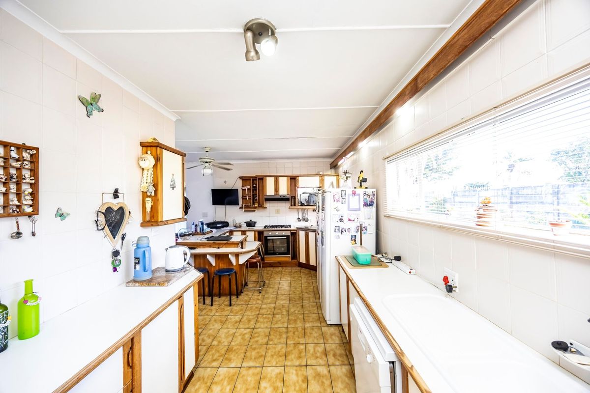 A functional kitchen featuring tiled flooring, wall-to-wall cabinetry, built-in oven and hob, and a double sink with ample counter space.
