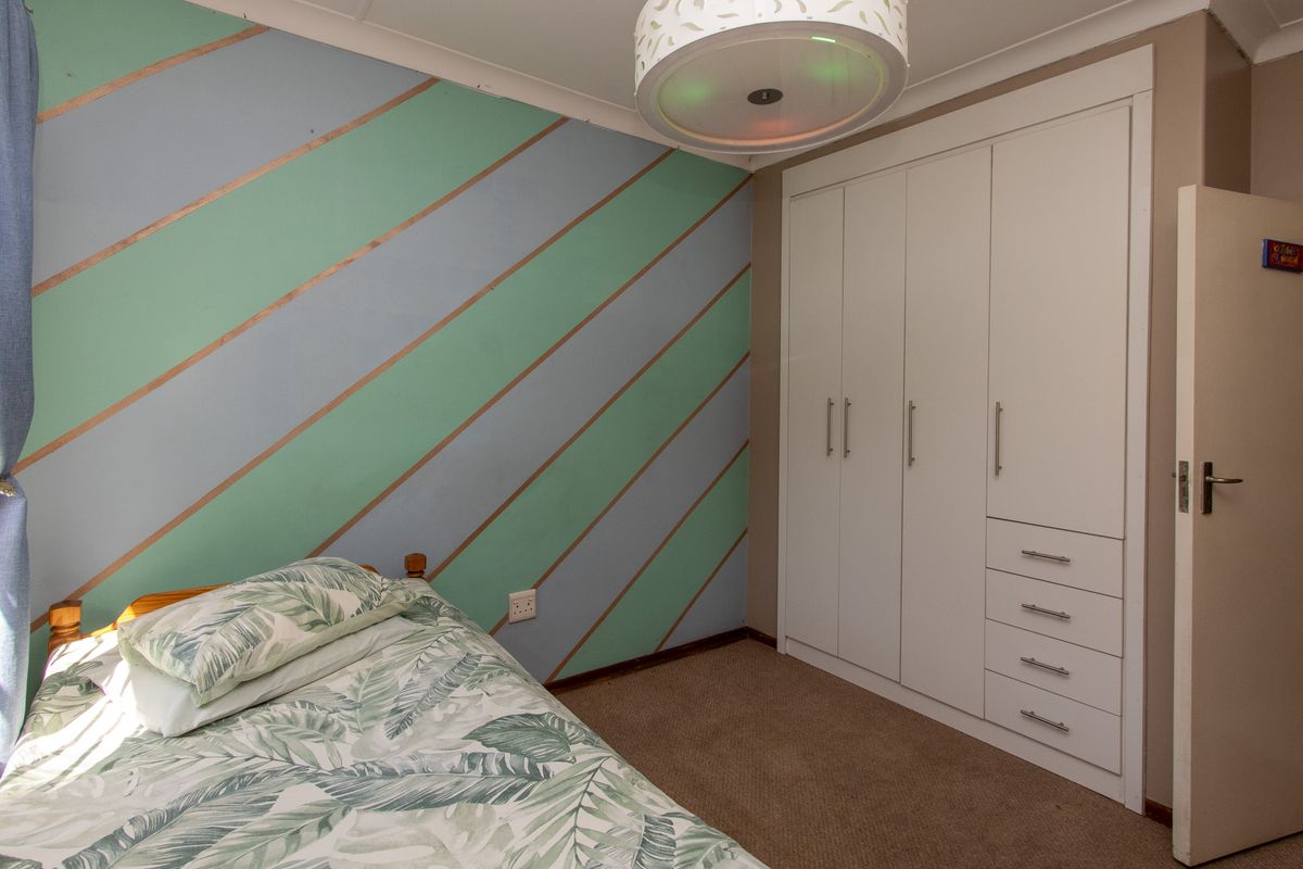 A bedroom featuring built-in wardrobes with ample storage, carpeted flooring, and a decorative painted feature wall.
