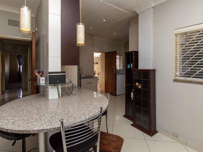 A functional kitchen area featuring a granite breakfast counter, tiled flooring, and built-in cabinetry with modern pendant lighting.