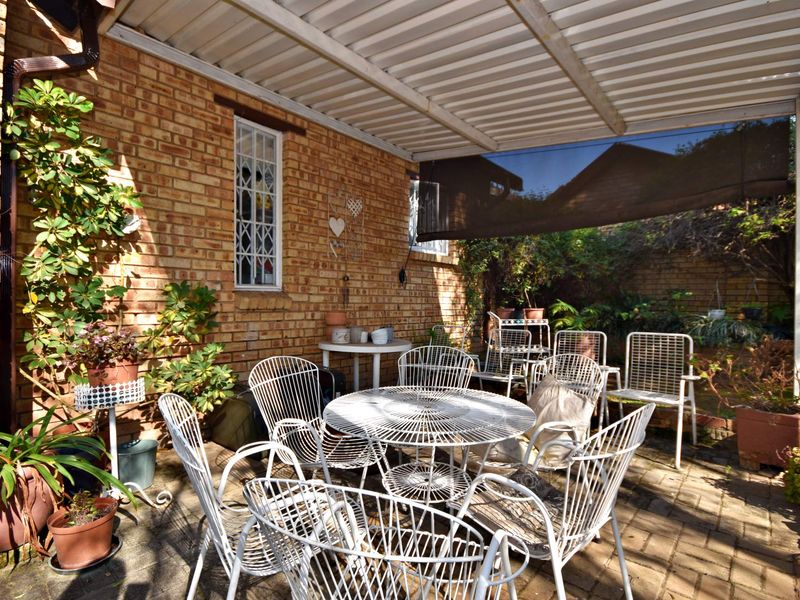 A covered outdoor patio area featuring brick walls, paved flooring, and a corrugated metal roof, providing a functional space for outdoor relaxation.