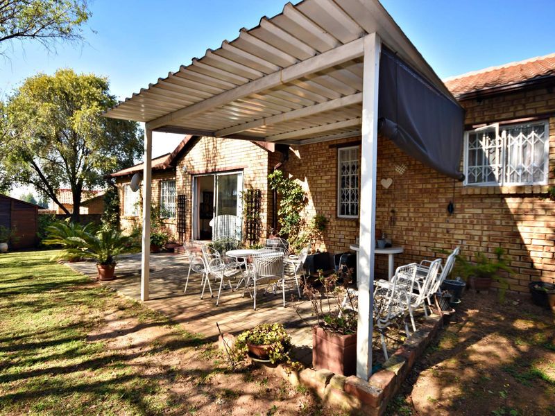 Rear exterior view of the townhouse featuring a paved patio area with a corrugated metal roof cover and direct access to the living space.