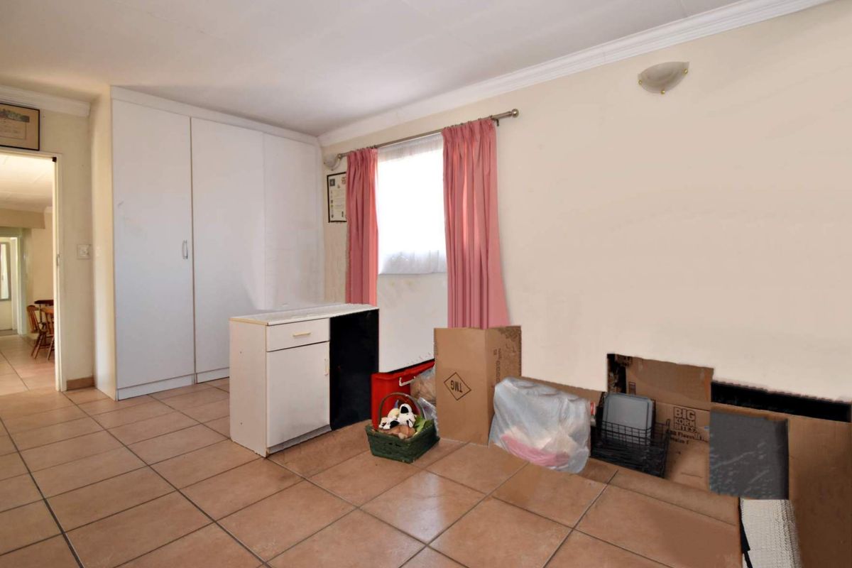 A bedroom featuring tiled flooring and built-in cupboards, currently requiring repairs to the wall and flooring.