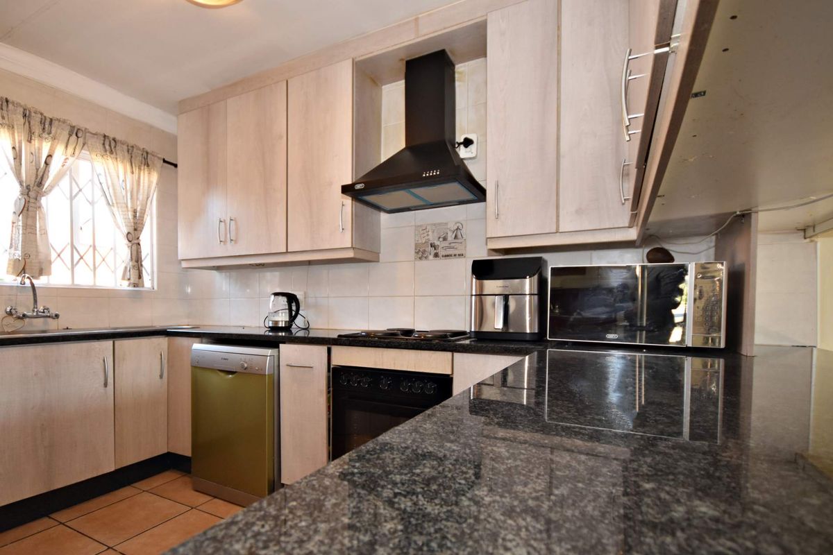 Functional kitchen featuring granite countertops, light wood-finish cabinetry, built-in oven with extractor fan, and tiled splashbacks.