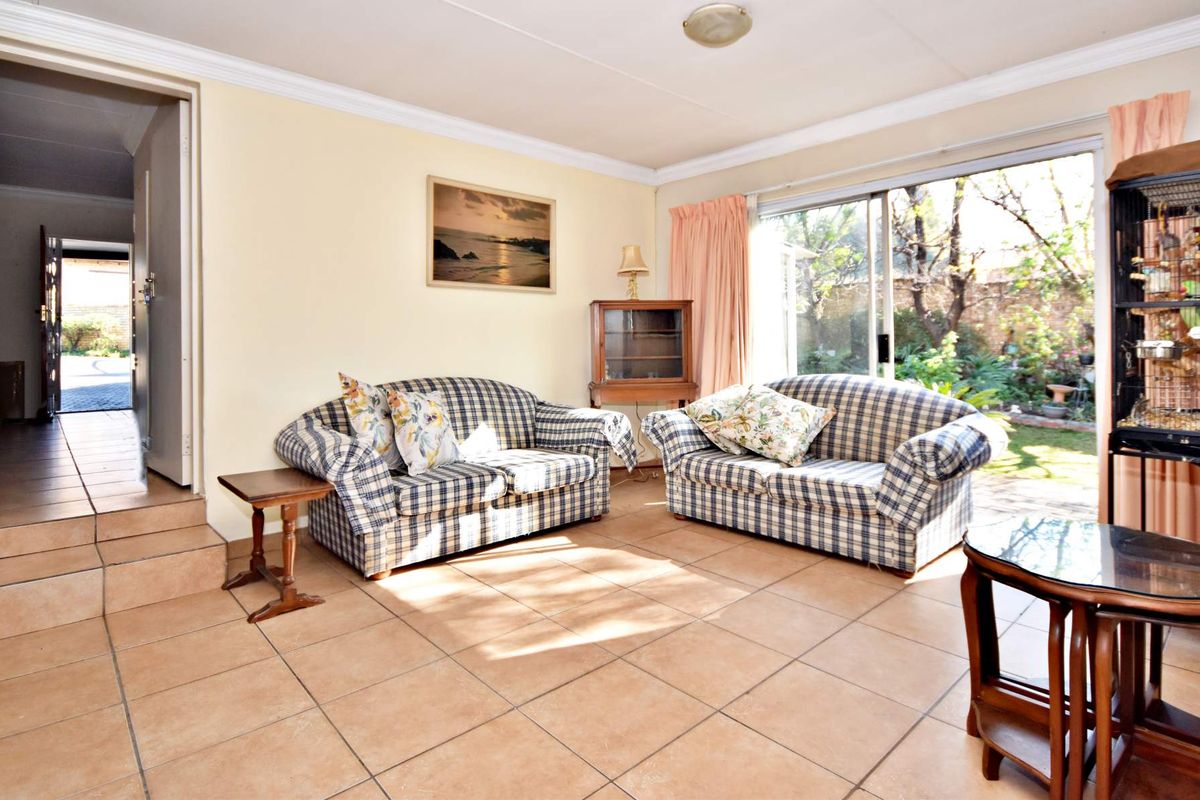 A living room featuring tiled flooring and a large sliding glass door providing access to the rear garden area.