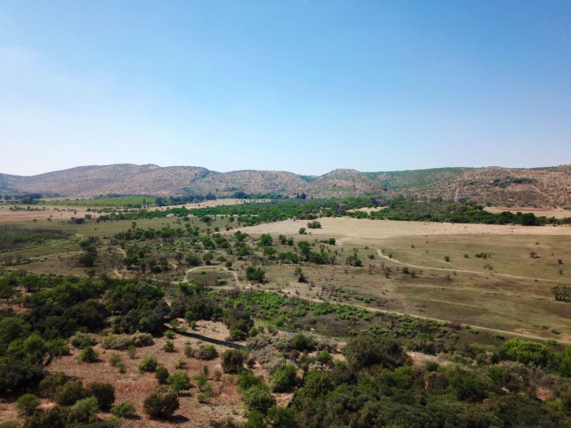An expansive aerial view of the surrounding natural landscape, featuring rolling hills, open fields, and indigenous vegetation.