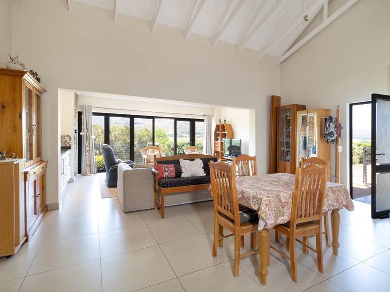 Spacious open-plan living and dining area featuring vaulted ceilings with exposed rafters, tiled flooring, and large bi-fold doors leading to the outdoors.