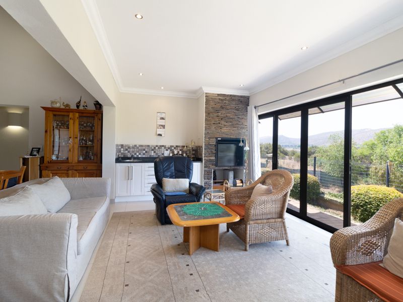 Spacious living room featuring a stone-clad fireplace, built-in wet bar, and large sliding glass doors providing natural light and access to the outdoor area.