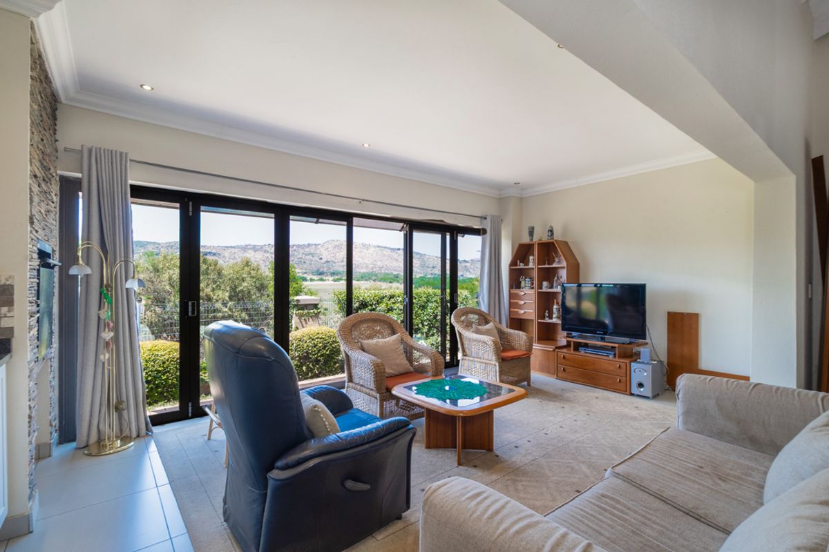 Spacious living room featuring a stone accent wall, recessed lighting, and large stacking glass doors that open to scenic mountain views.
