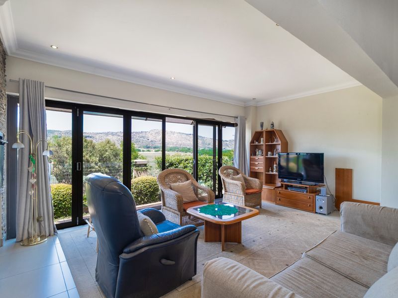 Spacious living room featuring a stone accent wall, recessed lighting, and large stacking glass doors that open to scenic mountain views.