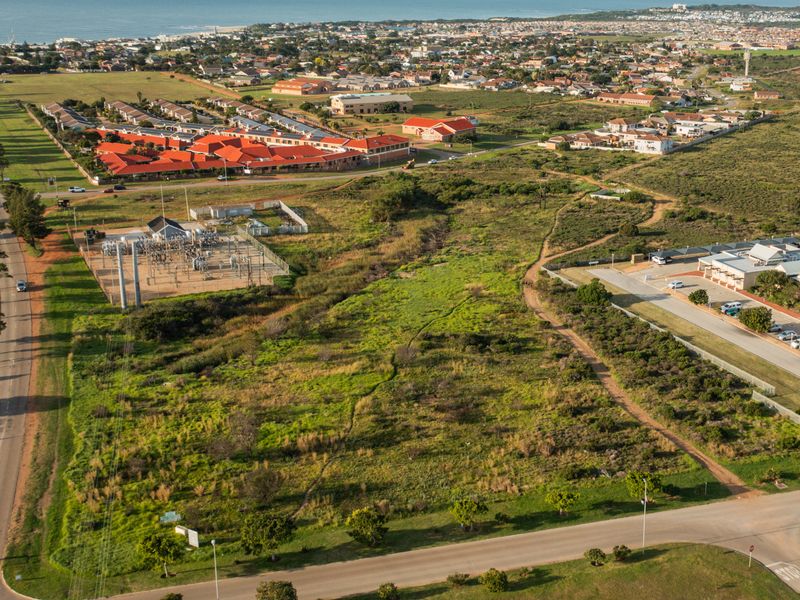 Aerial view of a vacant residential plot situated in a developed suburban area, featuring proximity to local infrastructure and road access.