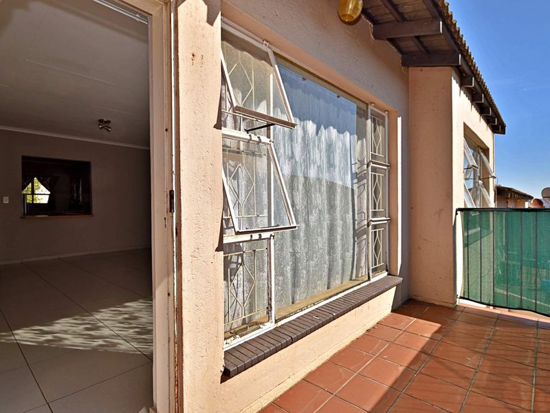 A covered balcony area featuring tiled flooring, metal security window bars, and direct access to the interior living space.