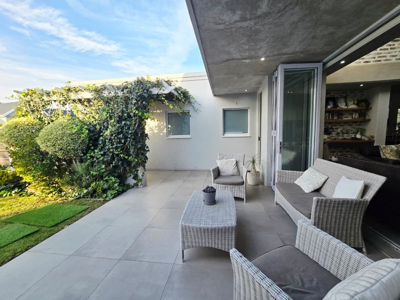 A modern covered patio featuring large format floor tiles, recessed lighting, and seamless bi-fold doors connecting to the indoor living space.