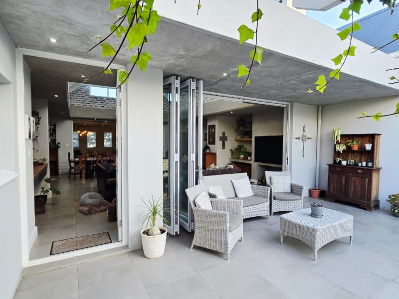 A spacious covered patio featuring large bi-fold doors that provide seamless indoor-outdoor flow, finished with modern floor tiles and recessed lighting.