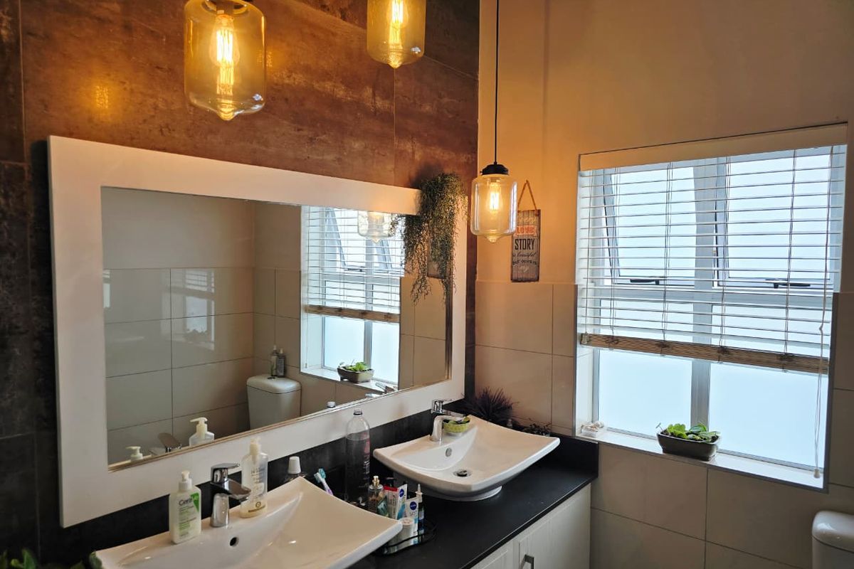 Modern bathroom featuring a double vanity with vessel sinks, large mirror, pendant lighting, and tiled wall finishes.