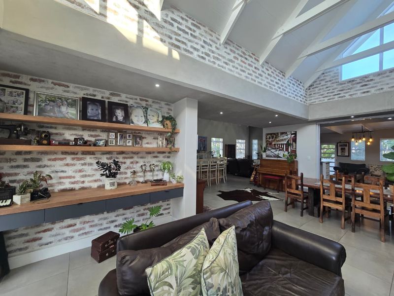 Spacious open-plan living area featuring high vaulted ceilings with exposed rafters, exposed brick feature walls, and modern tiled flooring throughout.